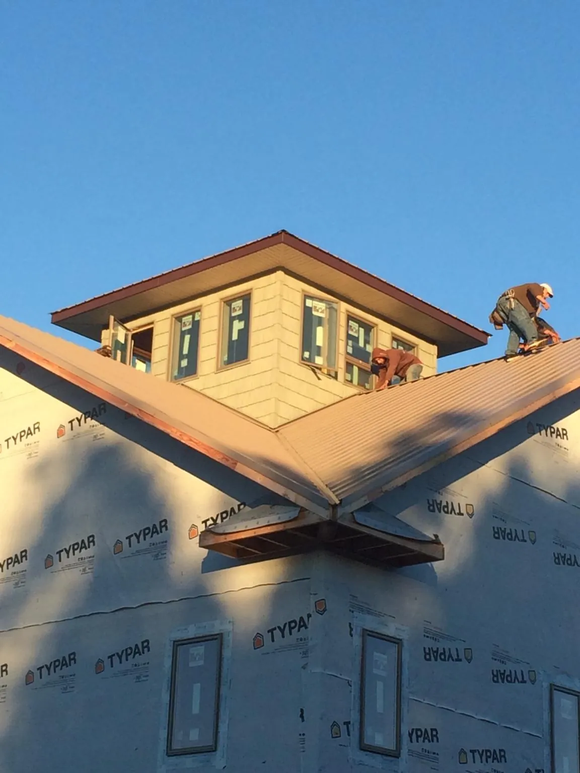 Roofers working around a rooftop cupola on a new metal roof at sunset — Roof Waterproofing in Rosedale by Roofing Brothers